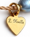 Engraved gold L. Noelle heart signature tag